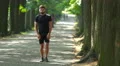 Sportsman stretch in the beautiful park alley. Slow motion. Super telephoto lens 4k or 4k+ Resolution