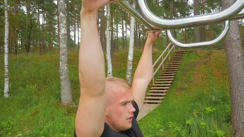 Sportsman training in park doing pull ups on horizontal bar Stock Footage 83819026