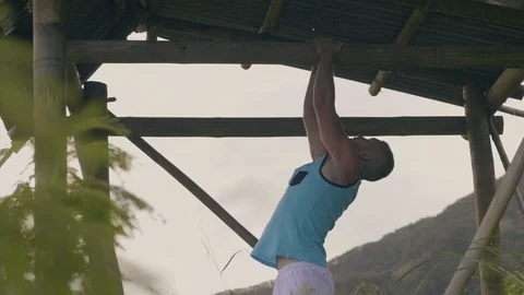 Sportsman training pull up exercise on horizontal bar on green mountain Stock Footage 107138919