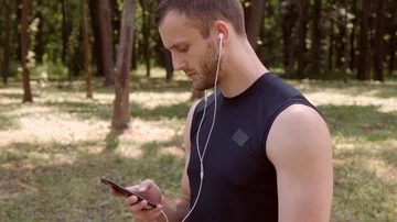 Sportsman using a mobile phone to switch music on the playlist before running Stock Footage 86041459