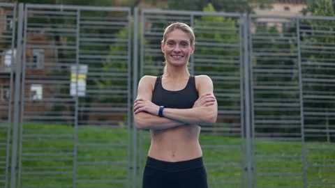 Sportswoman in activewear posing on camera while standing on stadium and smiling Stock Footage 252200075