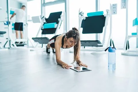 Sportswoman browsing tablet while doing plank Stock Photos