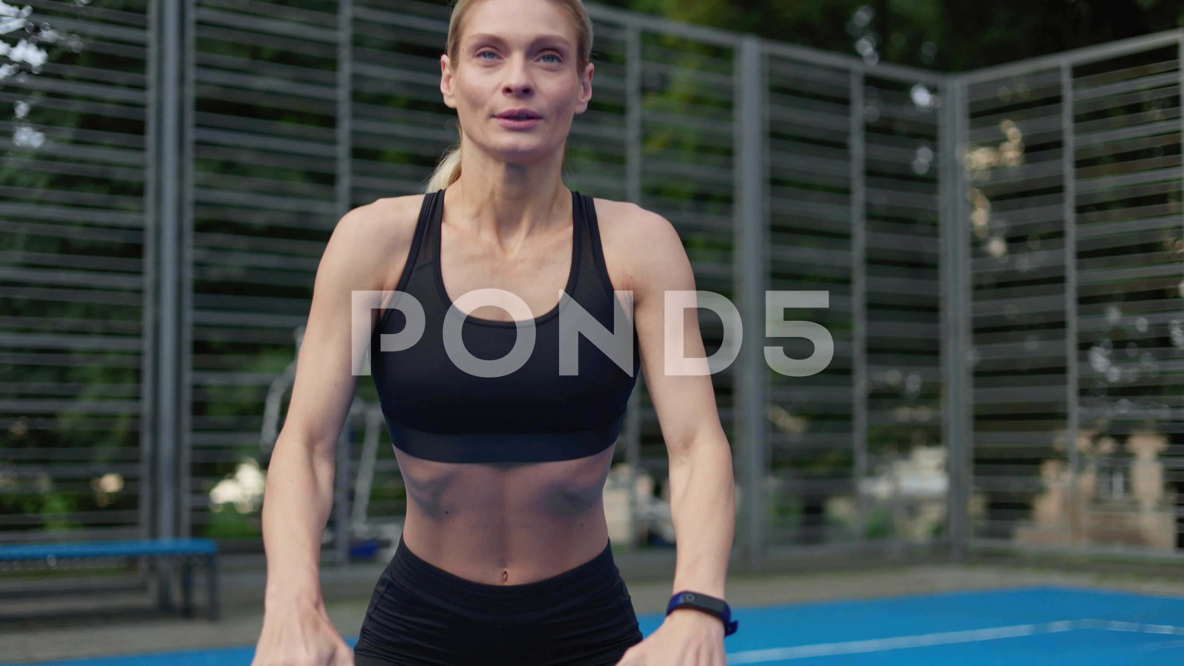 Sportswoman doing squat exercises with resistance band on street stadium