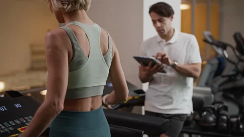 Sportswoman Practicing Treadmill Exercise while Coach Observing with Tablet Vidéo 328338594