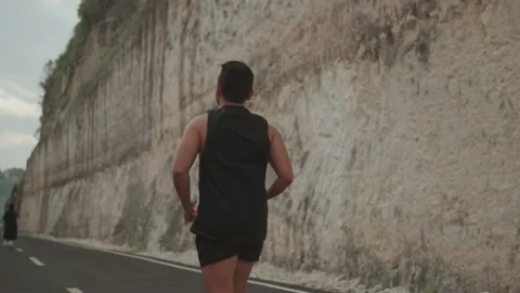Sporty Active Man Running on The Road Between Wall of Rocks in Slow Motion Stock Footage 233051639