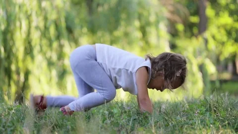 Sporty cute little girl doing mountain climbers exersice on the meadow at park Stock Footage