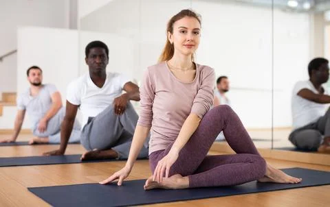 Sporty girl practicing Matsyendrasana during group yoga training Stock Photos