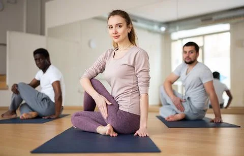 Sporty girl practicing Matsyendrasana during group yoga training Stock Photos