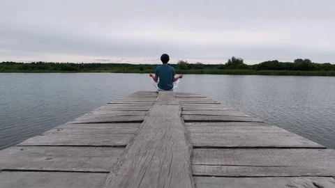 Sporty guy caucasian appearance practicing yoga on the nature near the lake Stock Footage 81129897