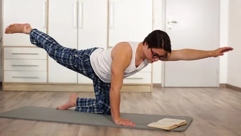 Sporty guy doing plank with opposite arm and leg lift on mat in living room Vidéo 259489727