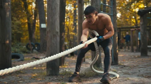 Sporty guy pulling a heavy tyre by a long rope. Man with naked torso workout  Stock Footage 165225045