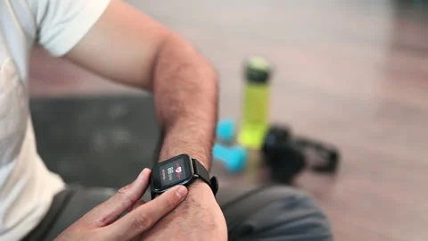 Sporty man checking pulse on smartwatch after workout inside Stock Footage 236539666