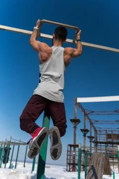 Sporty man doing pull up exercise outdoors Stock Photos