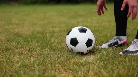 Sporty man hands setting down traditional black and white soccer ball on grass Video stock 278117033