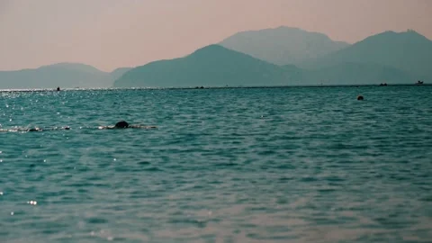 Sporty man in a swimming cap swims in the sea at the Hong Kong beach in sunshine Stock Footage