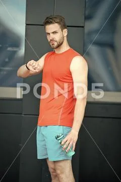 Sporty regime. Man athlete check time hold bottle care hydration body after Stock Photos