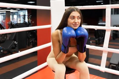 Sporty woman in boxing gloves resting while sitting in the ring Stock Photos
