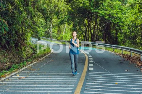 Sporty woman running on road at sunrise. Fitness and workout wellness concept Stock Photos
