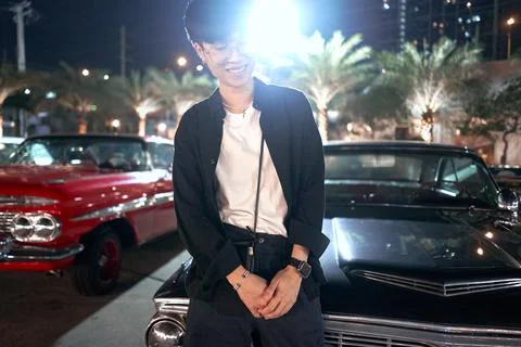 Spotlight illuminating a non-binary person in a fair parking with luxury cars Stock Photos