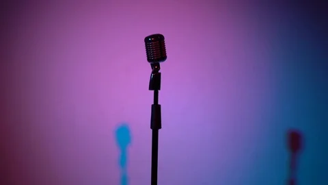 Spotlights shine on a chrome mic in middle on multi color background. Stock-Footage 118529117