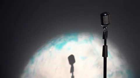 Spotlights shine on a chrome mic on the right on multi color background. Stock Footage 118527285