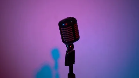 Spotlights shine on chrome mic on violet background. The camera moves away. Stock Footage 118544115