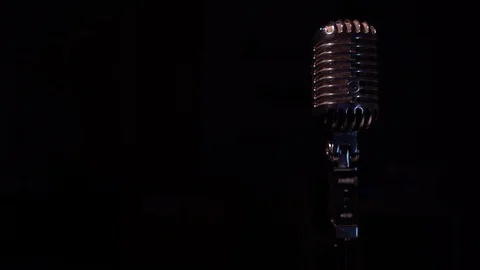 Spotlights shine on a chrome retro mic with flare on right on black background. Stock Footage 118528772