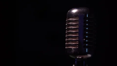 Spotlights shine on a chrome retro mic on black background and turn off. Video stock 118528904