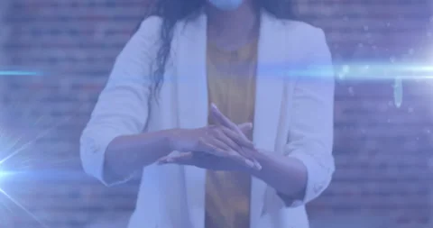 Spots of light against mid section of woman wearing face mask using hands Stock Footage 148362299