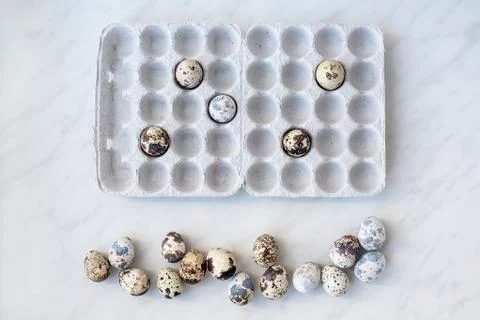 Spotted quail eggs on marble surface and cardboard box with eggs Stock Photos