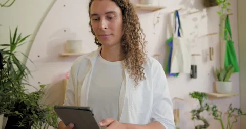 Spotting crooked vases nonbinary florist in plant shop fixing shelves tapping Stock Footage 340982246