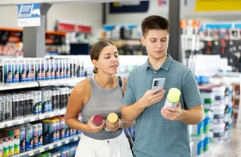 Spouses scans product QR code with phone on color aerosol in paint and vanish Stock Photos