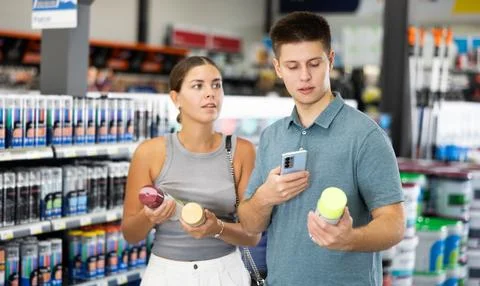 Spouses scans product QR code with phone on color aerosol in paint and vanish Stock Photos