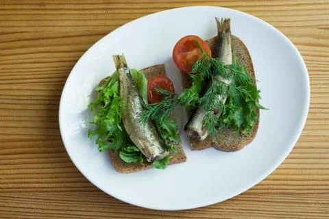 Sprats, bread and tomatoes on a saucer Foto stock