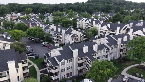 Sprawling apartment complex with angled gray rooftops fills wooded property in Stock Footage 342317523