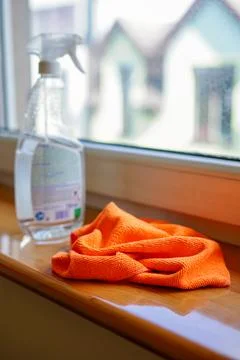 Spray bottle and orange microfiber cloth on a windowsill ready for cleaning Stock Photos