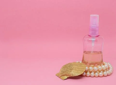 A spray bottle filled with liquid, a seashell and a pearl necklace Stock Photos
