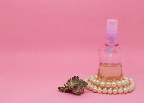 A spray bottle filled with liquid, a seashell and a pearl necklace Foto stock