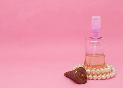 A spray bottle filled with liquid, a seashell and a pearl necklace Foto stock