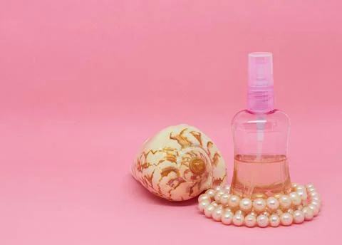 A spray bottle filled with liquid, a seashell and a pearl necklace Stock Photos
