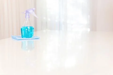 Spray bottle with liquid on a white table Stock Photos