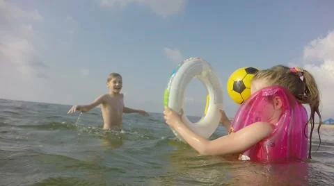 Spray flew at the camera. Children throw the ball in the sea. Slow motion. Video stock 64752226