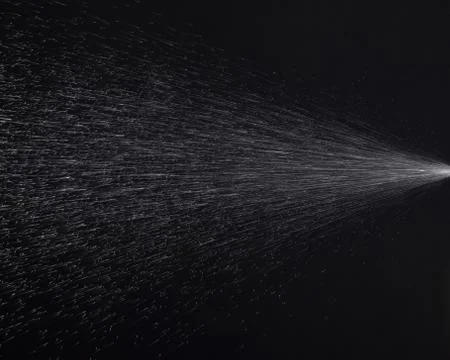 A spray of liquid in a black background. Stock Photos