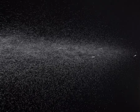 A spray of liquid in a black background. Stock Photos