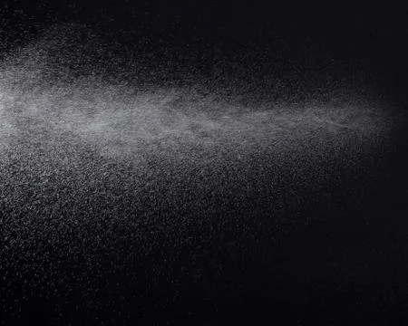 A spray of liquid in a black background. Stock Photos