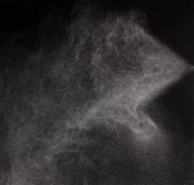 A spray of liquid in a black background. Stock Photos