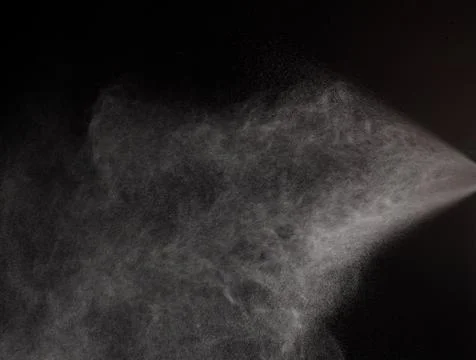 A spray of liquid in a black background. Stock Photos