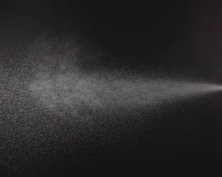 A spray of liquid in a black background. Stock Photos