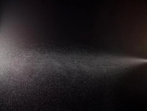 A spray of liquid in a black background. Stock Photos