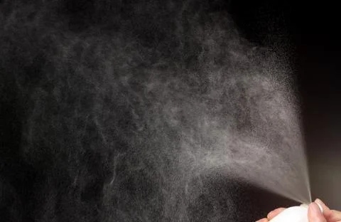 A spray of liquid in a black background. Stock Photos